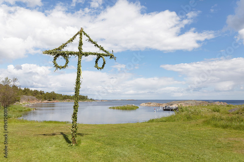 Tiny maypole in the Swedish archipelago, blue sky and white clouds in the background