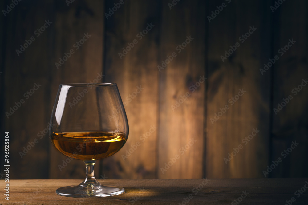 Glass of cognac on the wooden table Glass of cognac on the wooden table