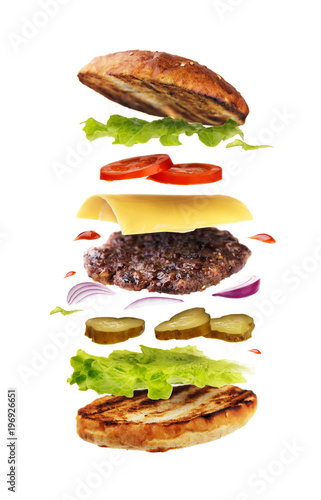 Delicious hamburger with flying ingredients isolated on white background. Freshly brewed burger closeup