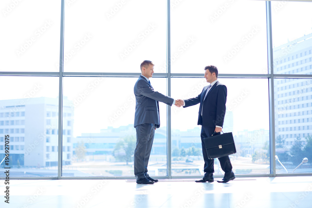Full length image of two successful business men shaking hands with each other Full length image of two successful business men shaking hands with each other