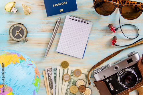 Conceptual tour planing image of travelling accessories on blue wooden background