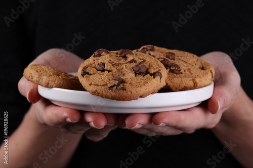 Woman holding plate with chocolate chip cookies.