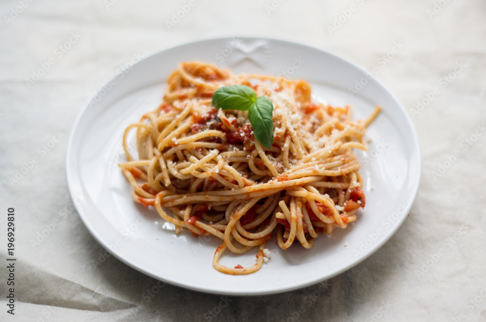 Homemade Italian pasta spaghetti with tomato sauce, fresh herbs and grated parmesan cheese on wooden rustic table