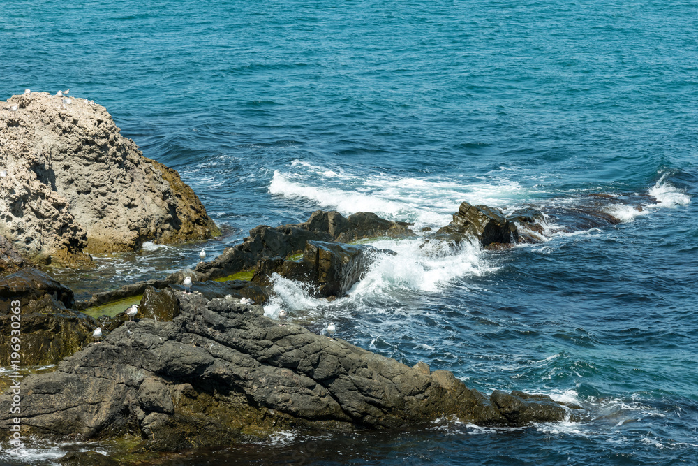 Blue sea, waves and rocky shore.