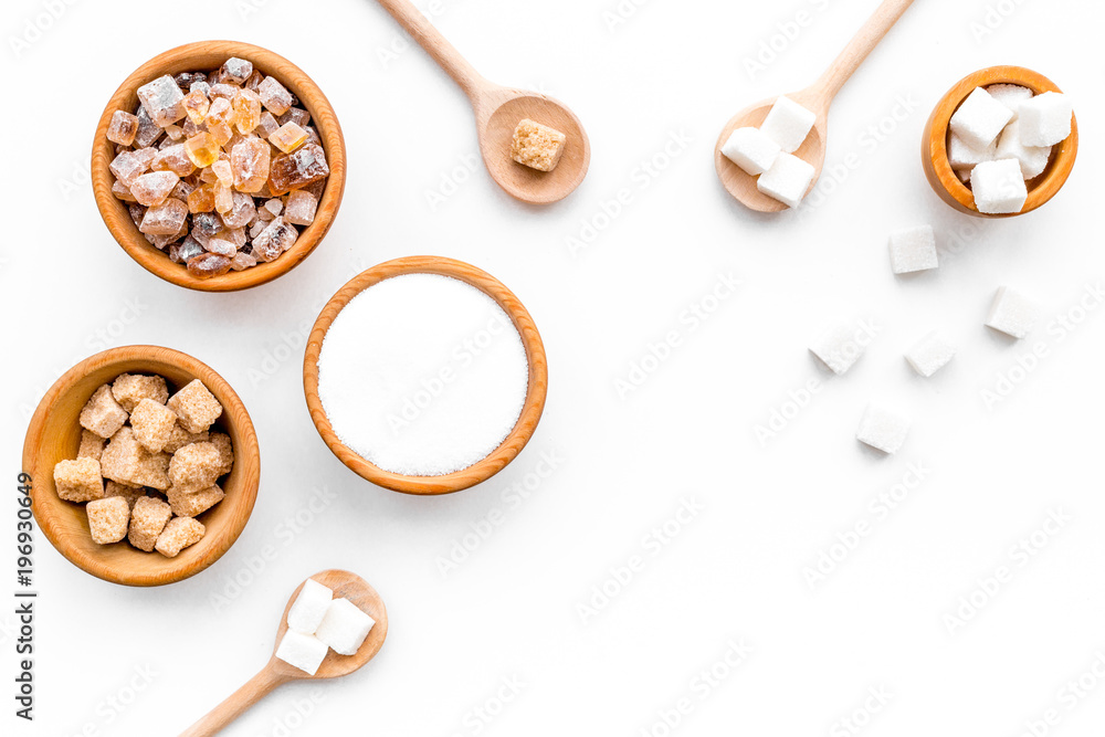 Brown and white sugar in bowls, scoop and spoon. Cane, refind, granulated, cubes, candy. White background top view copy space Brown and white sugar in bowls, scoop and spoon. Cane, refind, granulated, cubes, candy. White background top view copy space