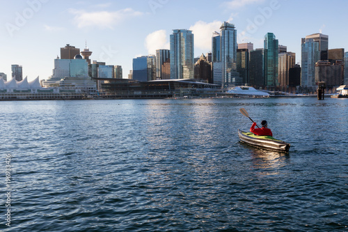 Man on an inflatable kayak is kayaking in Coal Harbour during a sunny morning. Taken in Downtown Vancouver, British Columbia, Canada.
