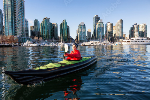 Man on an inflatable kayak is kayaking in Coal Harbour during a sunny morning. Taken in Downtown Vancouver, British Columbia, Canada.