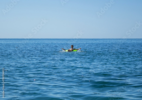 a young man swims on a large inflatable circle, on the sea © Vera