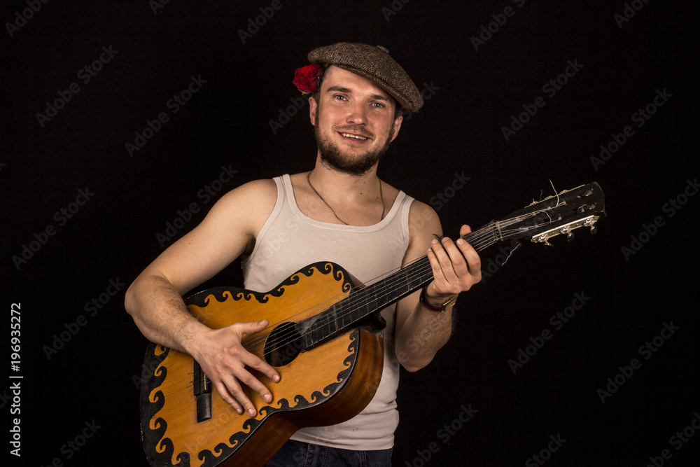Guitarist in a white T-shirt on a black background, with a rose behind his ear Guitarist in a white T-shirt on a black background, with a rose behind his ear