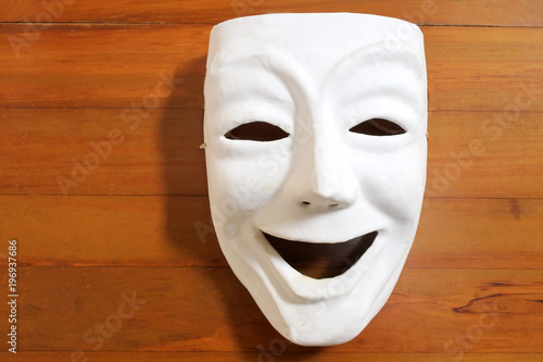 White happy human face expression mask with on a wooden table