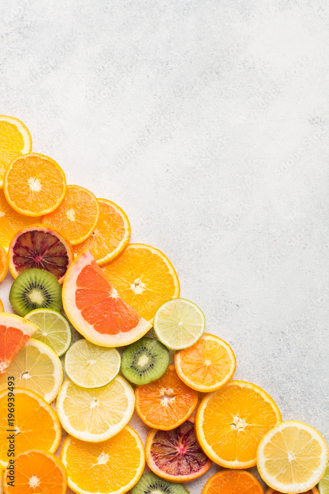 Assortment of citrus fruits and kiwis on white table background, top view, copy space, vertical, selective focus Assortment of citrus fruits and kiwis on white table background, top view, copy space, vertical, selective focus