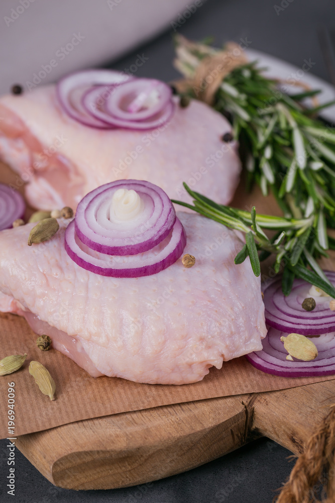 Raw chicken thighs with rosemary, red onion and peppercorns