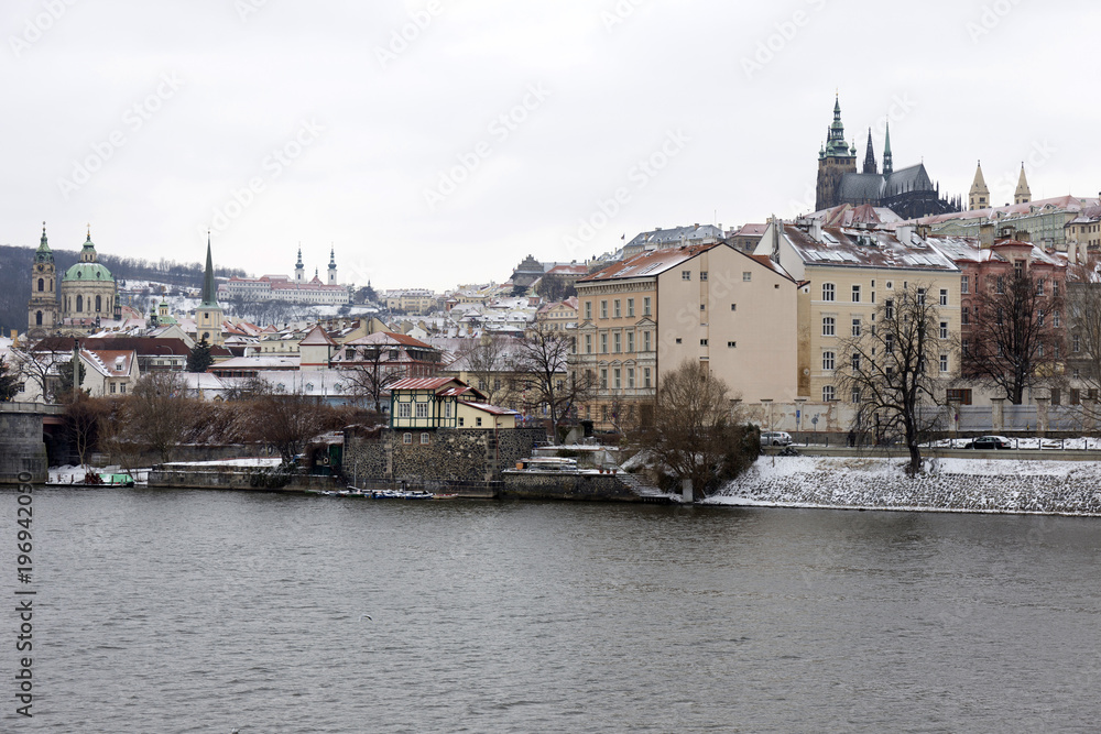 Obraz premium Snowy Prague Lesser Town with gothic Castle above River Vltava, Czech republic