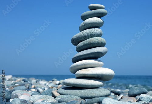 Φωτογραφία balance a pyramid of smooth stones on the background of the sea