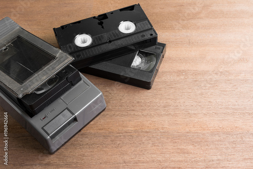 crack vhs rewinder and video cassette tape on wooden board with copy space. old technology concept.
