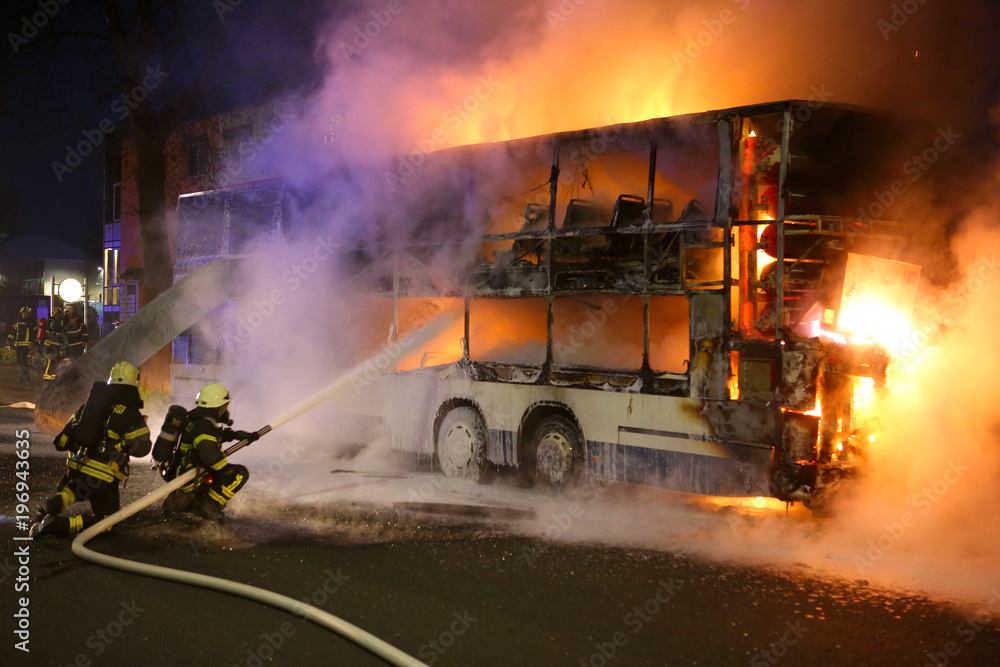 Feuerwehrleute löschen den Brand eines Doppeldecker-Busses Feuerwehrleute löschen den Brand eines Doppeldecker-Busses