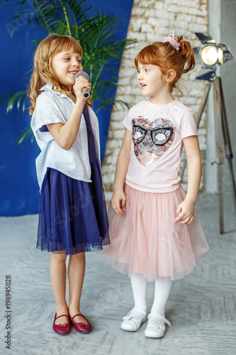 Two young children sing a song on a microphone. Group. The concept is childhood, lifestyle, music, singing, friendship.