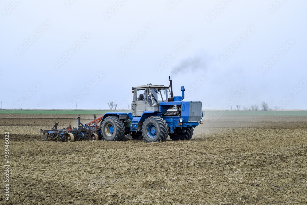 Lush and loosen the soil on the field before sowing. The tractor plows a field with a plow Lush and loosen the soil on the field before sowing. The tractor plows a field with a plow
