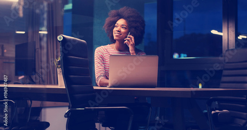 black businesswoman using a laptop in night startup office