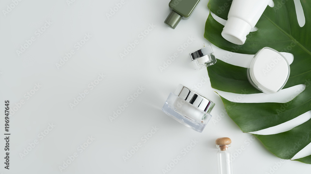 White cosmetic products and green leaves on white background. Natural beauty products for branding mock-up concept. White cosmetic products and green leaves on white background. Natural beauty products for branding mock-up concept.