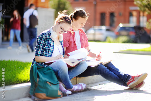 Young happy students with books and notes outdoors