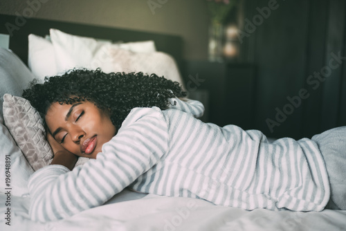 close up of a pretty black woman with curly hair sleeping in bed closed eyes