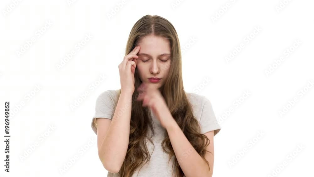 Portrait of exhausted or sick woman 17y massaging temples with fingers and suffering from strong headache, over white background. Concept of emotions Portrait of exhausted or sick woman 17y massaging temples with fingers and suffering from strong headache, over white background. Concept of emotions