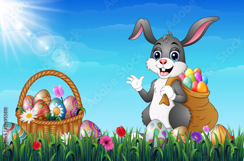 Easter bunny carrying sack full of easter eggs in a grass field
