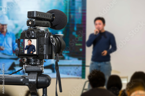 Professional digital Mirrorless camera with microphone on the tripod recording video blog of asian Speaker on the stage seminar, Camera for photographer or Video and Technology Live Streaming concept