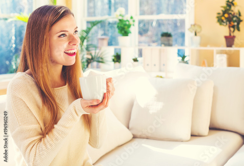 Happy young woman drinking coffee at home