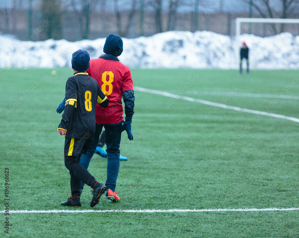 Fototapeta premium boys play football on the winter stadium