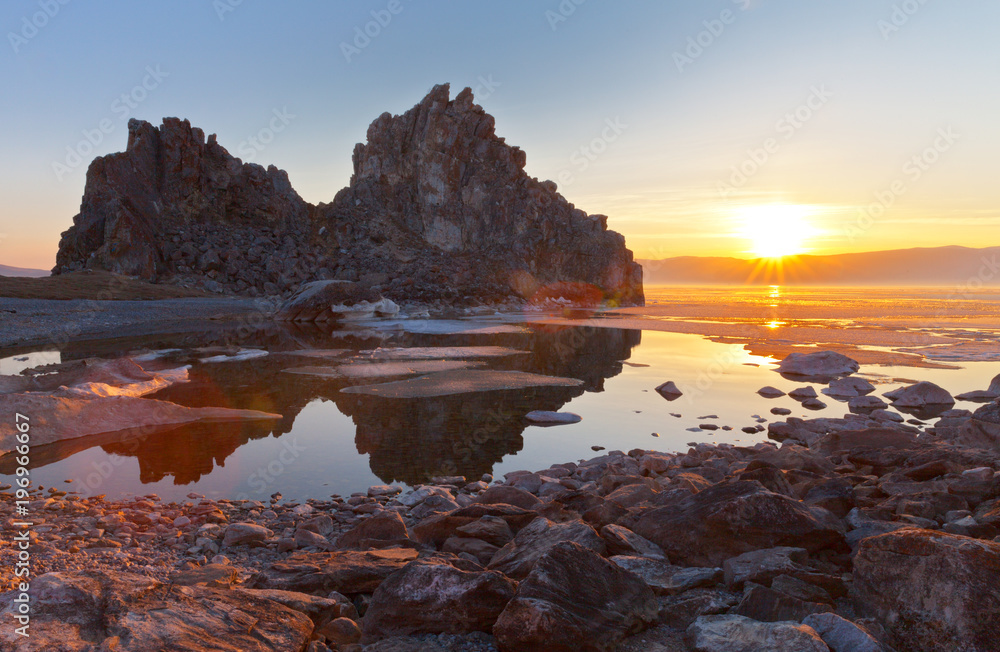 Lake Baikal. Beautiful spring landscape with melting ice in the bay near the Shamanka Rock at sunset