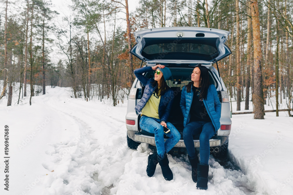 Two beautiful young women traveler traveling by car in winter. Travel background