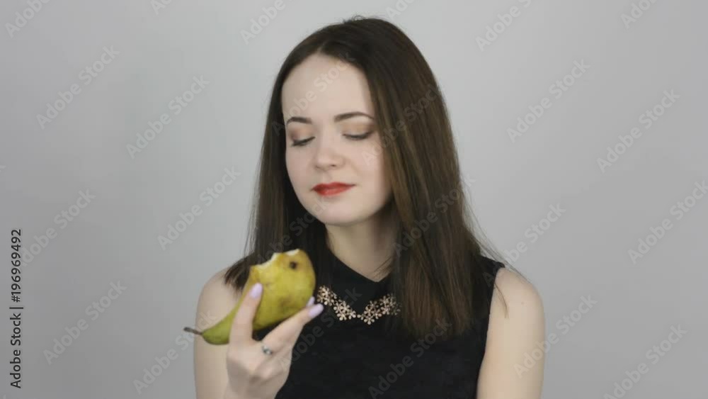 Beautiful young woman eats a green pear and smiles. Concept of eating fresh fruits vegetarian Beautiful young woman eats a green pear and smiles. Concept of eating fresh fruits vegetarian