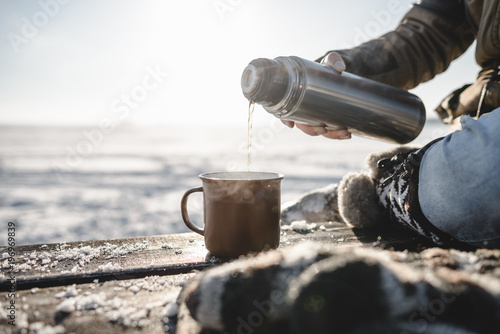 Pouring the tea from the thermos photo