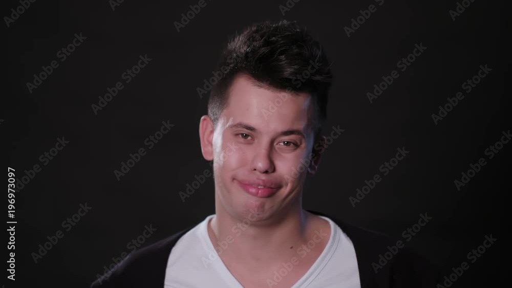 A young man biting his toungue against a black background. Close-up shot A young man biting his toungue against a black background. Close-up shot