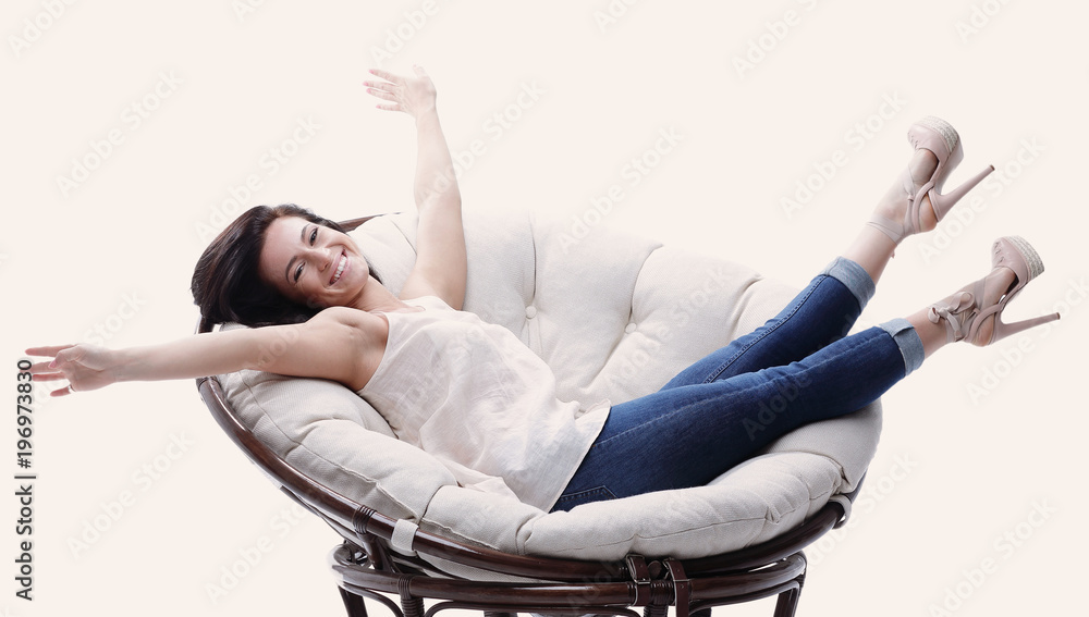 Obraz premium Modern young woman relaxing in a round cozy soft chair