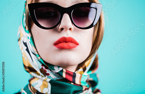 Close up shot of stylish young woman in sunglasses against blue background.