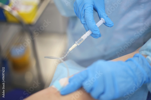 Nurse in blue latex gloves makes an injection to a patient in a hospital