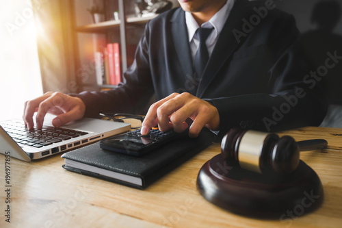  justice and law concept.businessman or lawyer or accountant working on accounts using a calculator and laptop computer and documents in modern office 