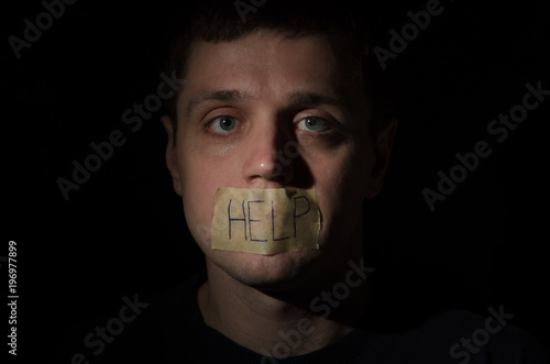 Tablou pe pânză Hostage chained in a chain praying for help with an inscription help on an adhes