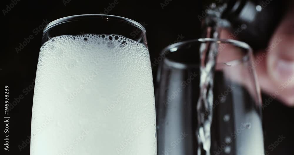 Two wine glasses with champagne bubbles on dark background