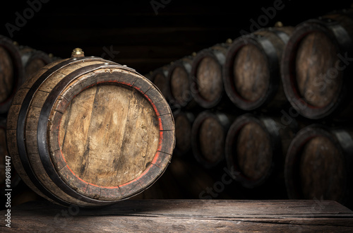 Wine barrel on the old wooden table. Wine cellar at the background.