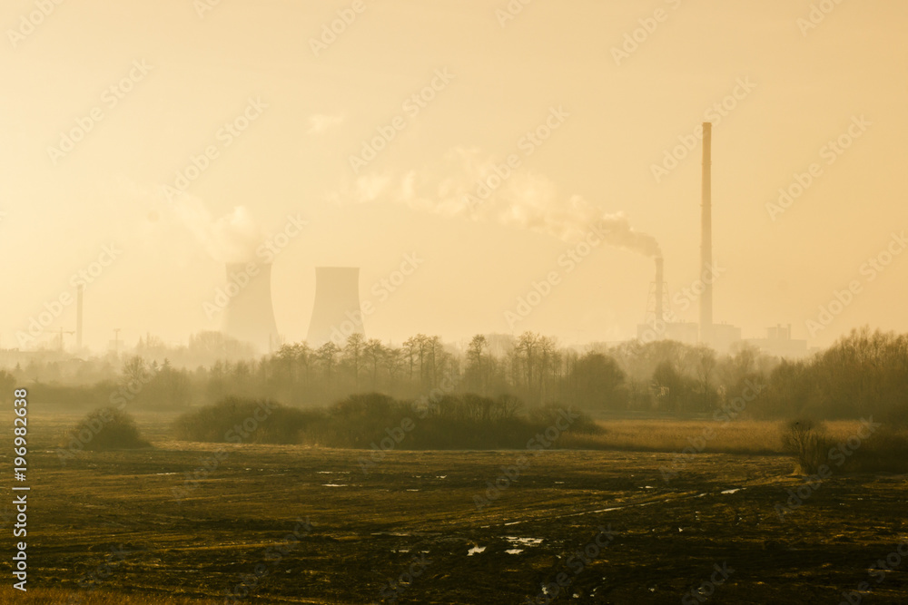 Nature landscape with factory and pipes of which goes smoke in the background, concept of environmental pollution