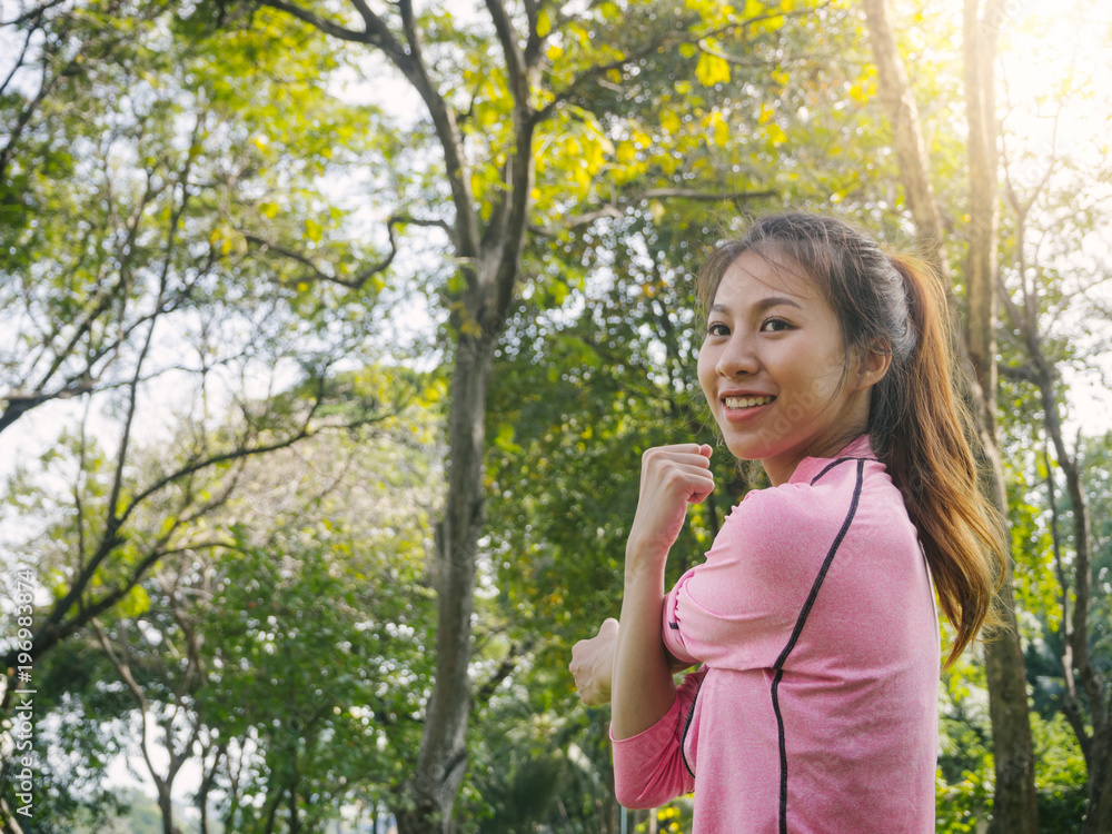 Close up of a young woman warm up her body by stretching her arms to be ready for exercising and do yoga in the park surrounded by nature and warm light afternoon sky. Outdoor workout exercise concept Close up of a young woman warm up her body by stretching her arms to be ready for exercising and do yoga in the park surrounded by nature and warm light afternoon sky. Outdoor workout exercise concept