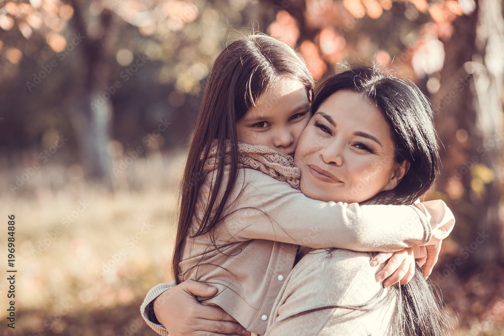 Fototapeta premium Close up image of mum and daughter holding each other in autumn garden.
