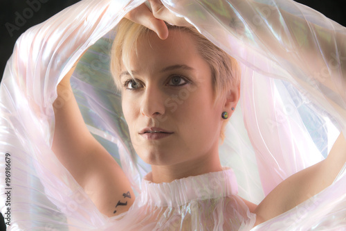 Striking portrait of young woman wrapped in gossamer cape.