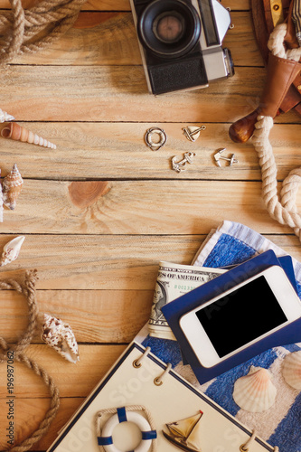 Striped towel, camera, phone and maritime decorations, top view