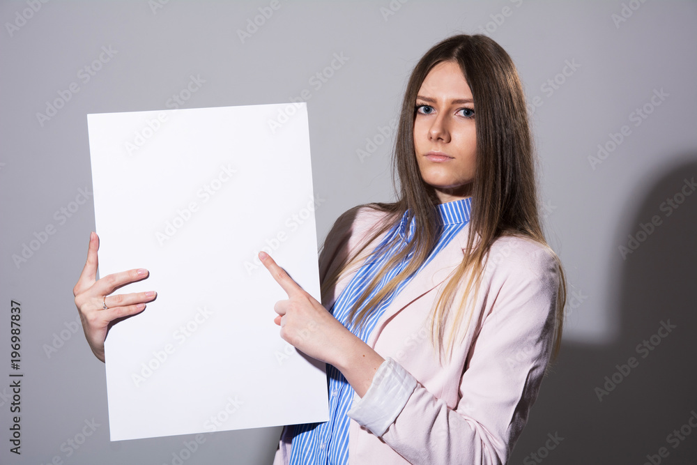 Young serious woman pointing at white sheet Young serious woman pointing at white sheet