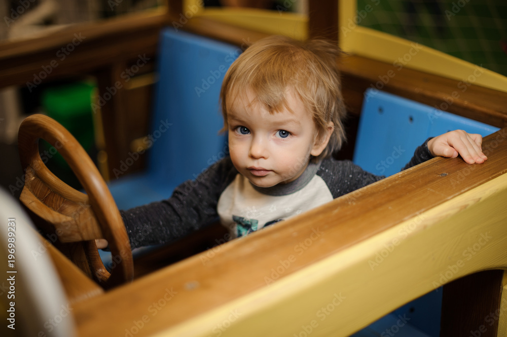 Cute little boy playing in the toy wooden car Cute little boy playing in the toy wooden car